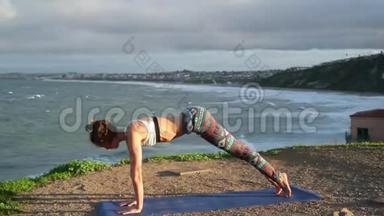 年轻女子在黎明或日落<strong>时</strong>在岩石上<strong>靠近</strong>海洋练习瑜伽。